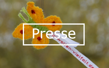 Gelber Häkel-Schmetterling mit grünem Körper und Wäscheband mit Aufschrift "wir-wollen-vielfalt.de". In der Mitte des Bildes steht das Wort "Presse".