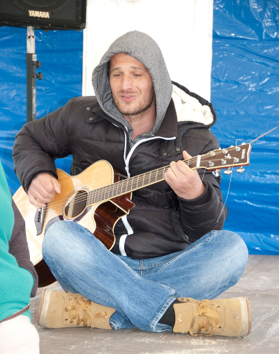 Sänger im Schneidersitz mit Gitarre