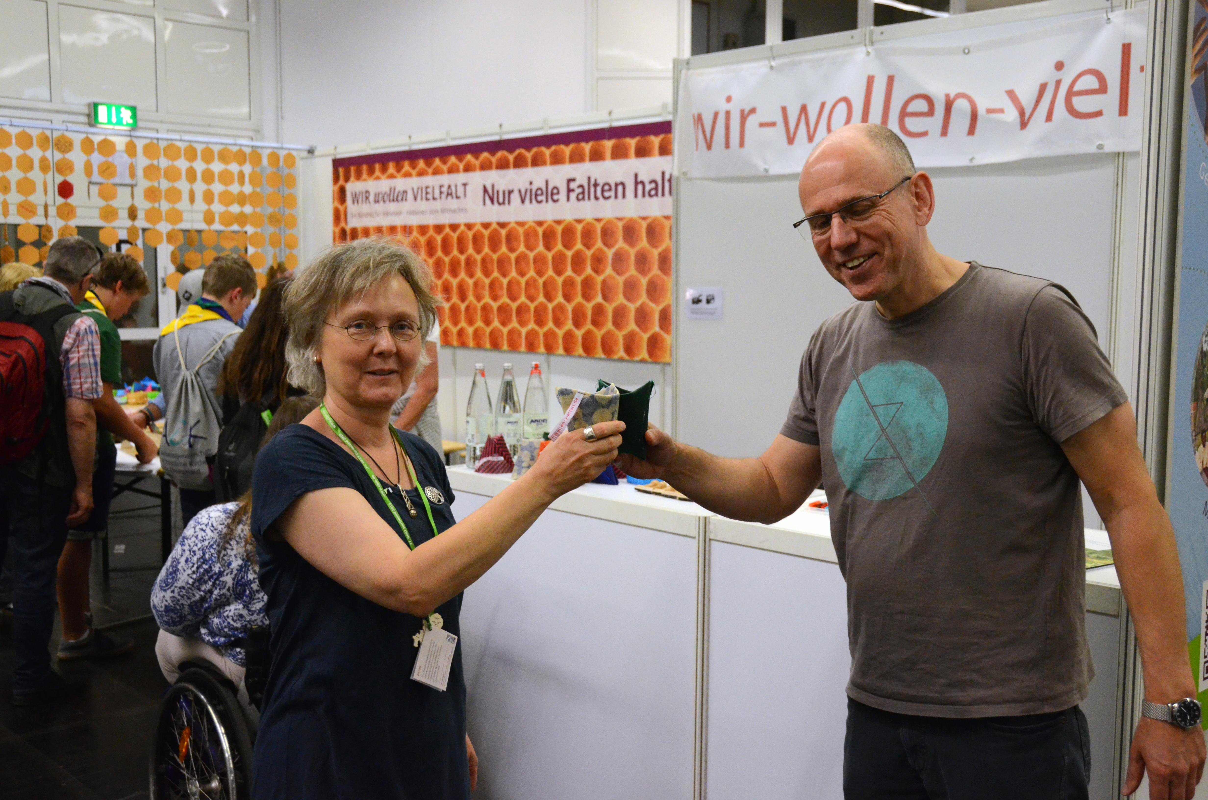 Zwei Kirchentags-Besucher stoßen mit Mineralwasser in Wachstuch-Bechern an.