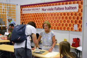 Eine Kirchentags-Besucherin bügelt Wachs auf ein Stück Stoff.