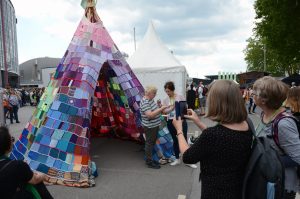 Eine Kirchentags-Besucherin macht ein Foto mit dem Tipi als Hintergrund.