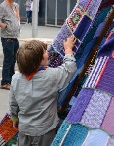 Ein Pfadfinder-Wölfling streicht mit der Hand über die gehäkelte Zelthaut.