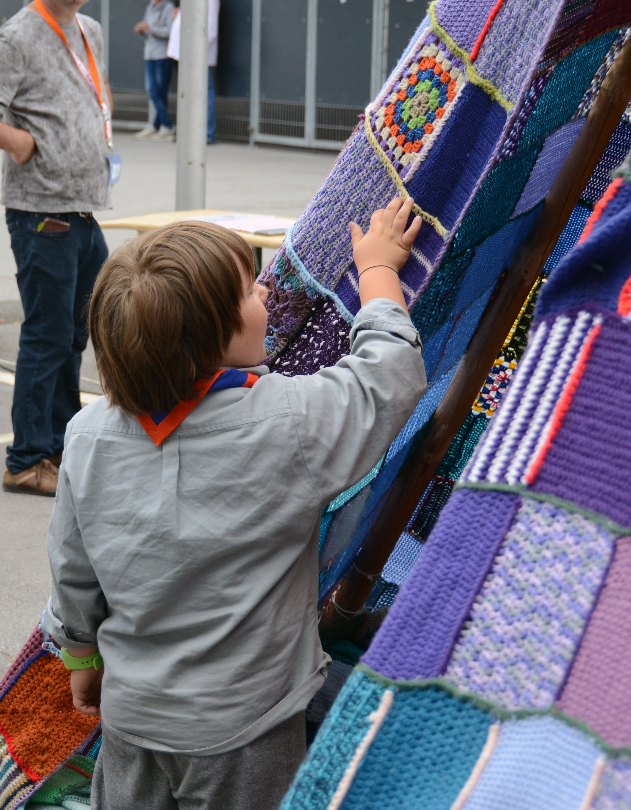 Ein Pfadfinder-Wölfling streicht mit der Hand über die gehäkelte Zelthaut.